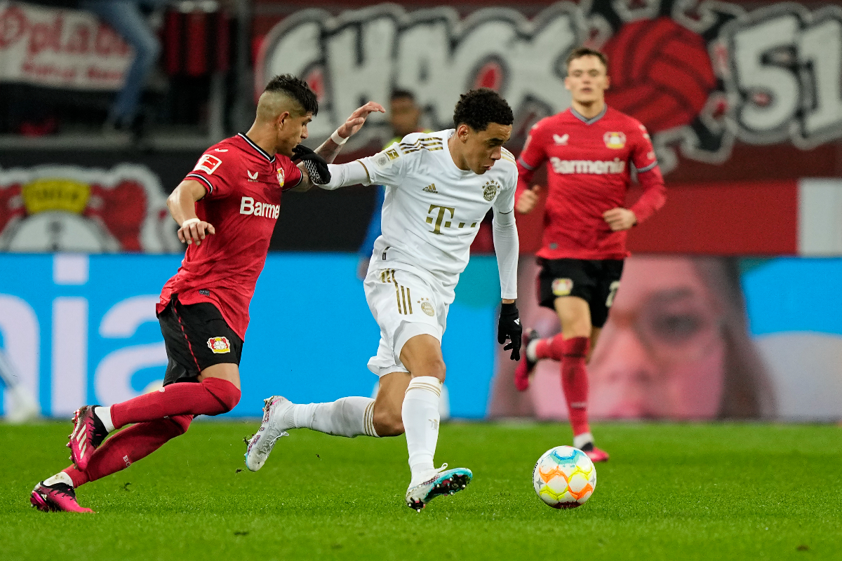 FILE - Bayern's Jamal Musiala, center, and Leverkusen's Piero Hincapie, left, challenge for the ball during the German Bundesliga soccer match between Bayer Leverkusen and Bayern Munich in Leverkusen, Germany, Sunday, March 19, 2023. Bayern Munich hosts Bayer Leverkusen when the Bundesliga returns from the international break with its biggest game of the season so far. Something will need to give on Friday between the only two teams remaining with perfect records. Leverkusen has racked up 11 goals in three wins from three games and leads on goal difference from Bayern. (AP Photo/Martin Meissner, File)