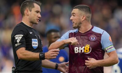 Referee Jarred Gillett, left, discusses with Aston Villa's John McGinn during the English Premier League soccer match between Chelsea and Aston Villa at Stamford Bridge stadium in London, Sunday, Sept. 24, 2023. (AP Photo/Alastair Grant)