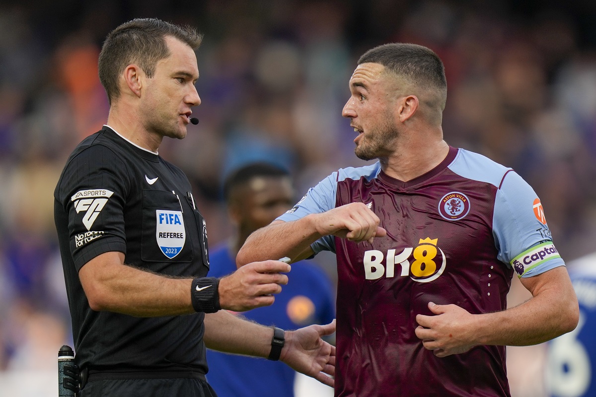 Referee Jarred Gillett, left, discusses with Aston Villa's John McGinn during the English Premier League soccer match between Chelsea and Aston Villa at Stamford Bridge stadium in London, Sunday, Sept. 24, 2023. (AP Photo/Alastair Grant)