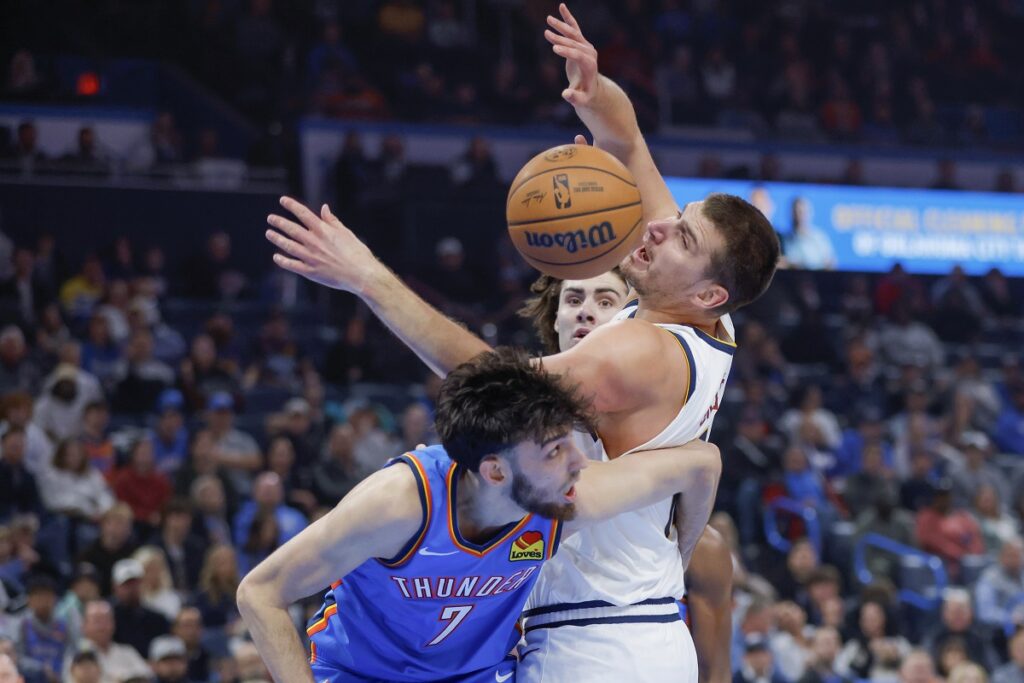 Denver Nuggets center Nikola Jokic, right, tries to grab a rebound between Oklahoma City Thunder forward Chet Holmgren (7) and guard Josh Giddey, back, in the first half of an NBA basketball game, Sunday, Oct. 29, 2023, in Oklahoma City. (AP Photo/Nate Billings)
