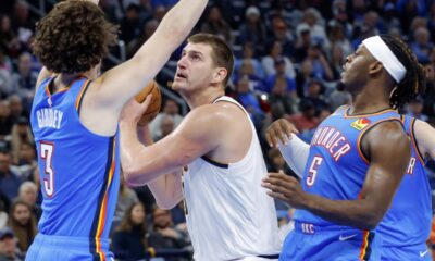 Denver Nuggets center Nikola Jokic, center, looks to score between Oklahoma City Thunder guards Josh Giddey (3) and Luguentz Dort (5) in the first half of an NBA basketball game, Sunday, Oct. 29, 2023, in Oklahoma City. (AP Photo/Nate Billings)