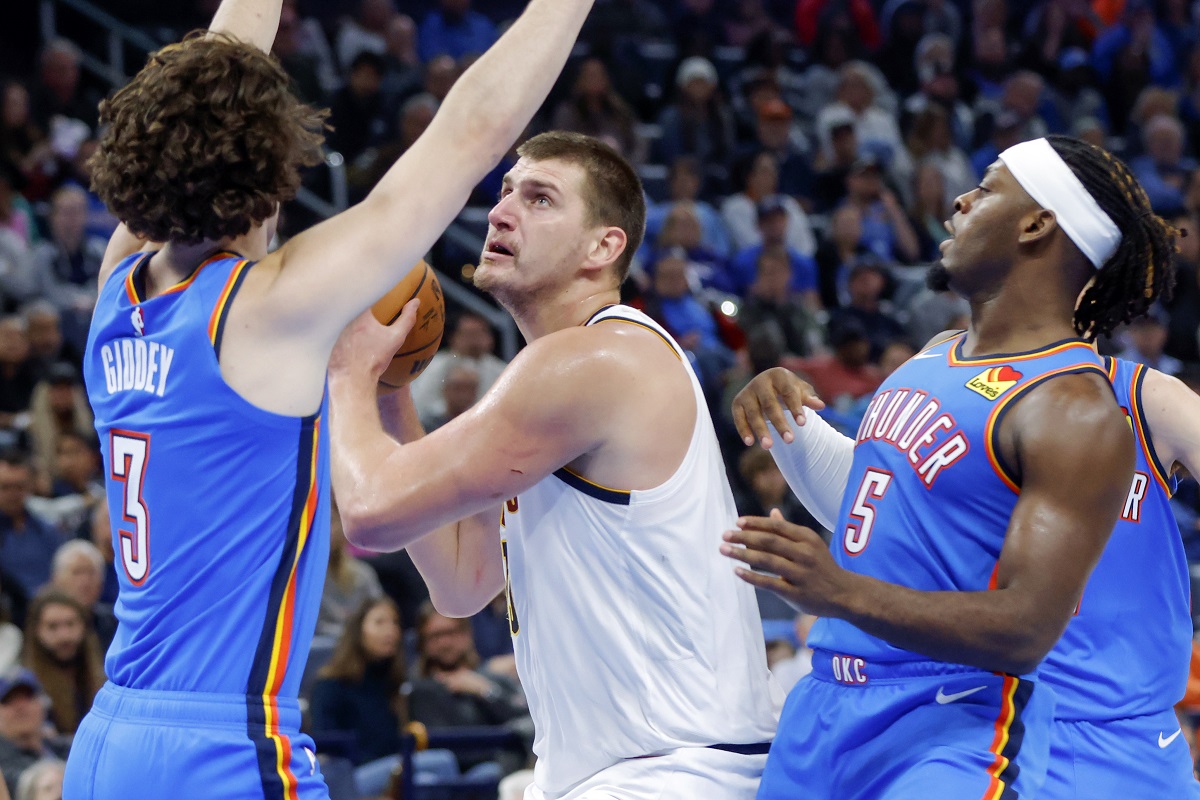 Denver Nuggets center Nikola Jokic, center, looks to score between Oklahoma City Thunder guards Josh Giddey (3) and Luguentz Dort (5) in the first half of an NBA basketball game, Sunday, Oct. 29, 2023, in Oklahoma City. (AP Photo/Nate Billings)