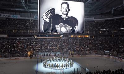 The Pittsburgh Penguins and Anaheim Ducks gather at center ice, before an NHL hockey game in Pittsburgh, Monday, Oct. 30, 2023, to honor former Penguin player Adam Johnson, shown on scoreboard, who died in while playing in an English hockey league game. (AP Photo/Gene J. Puskar)