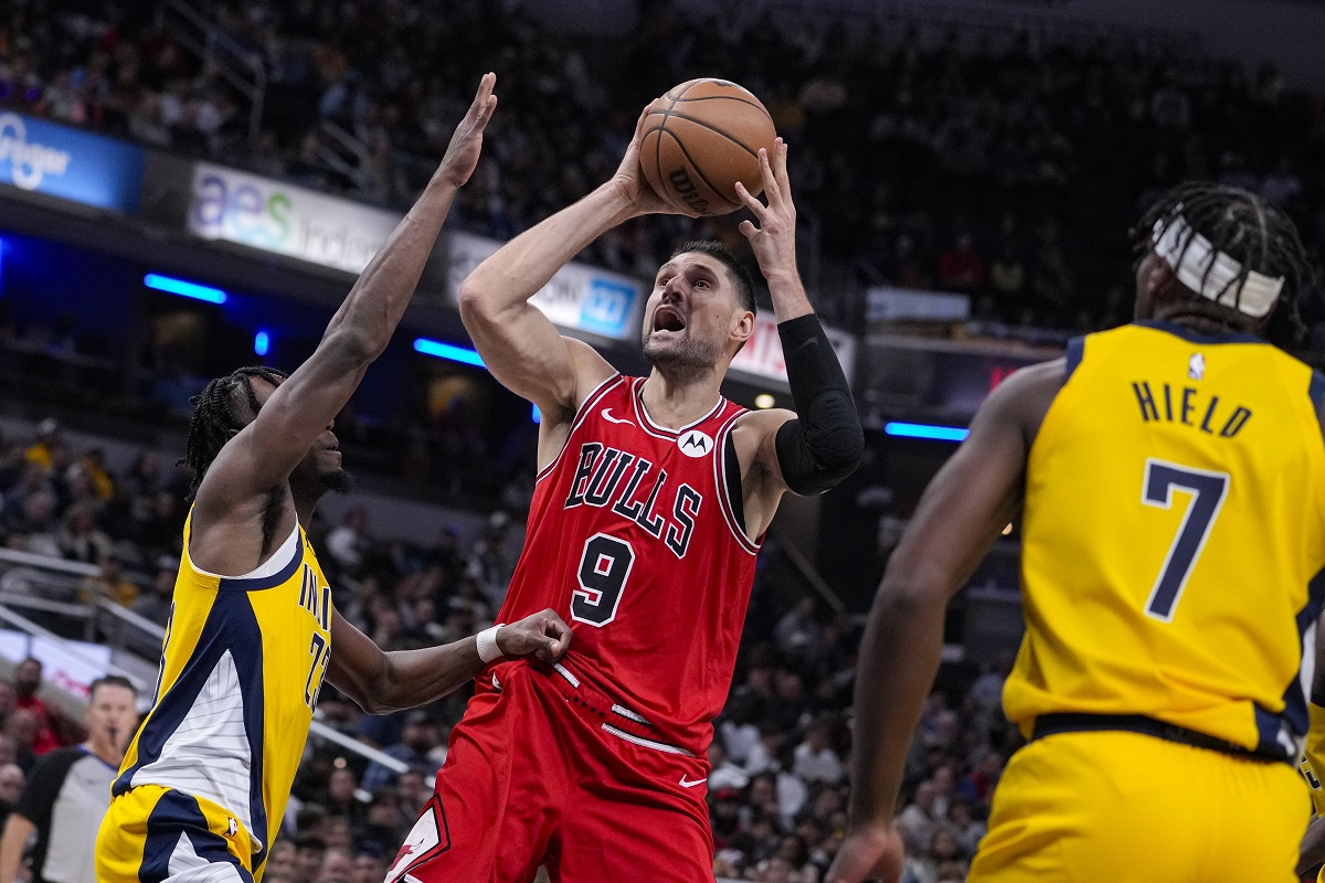 Chicago Bulls center Nikola Vucevic (9) shoots between Indiana Pacers forward Aaron Nesmith (23) and guard Buddy Hield (7) during the second half of an NBA basketball game in Indianapolis, Monday, Oct. 30, 2023. The Bulls defeated the Pacers 112-105. (AP Photo/Michael Conroy)
