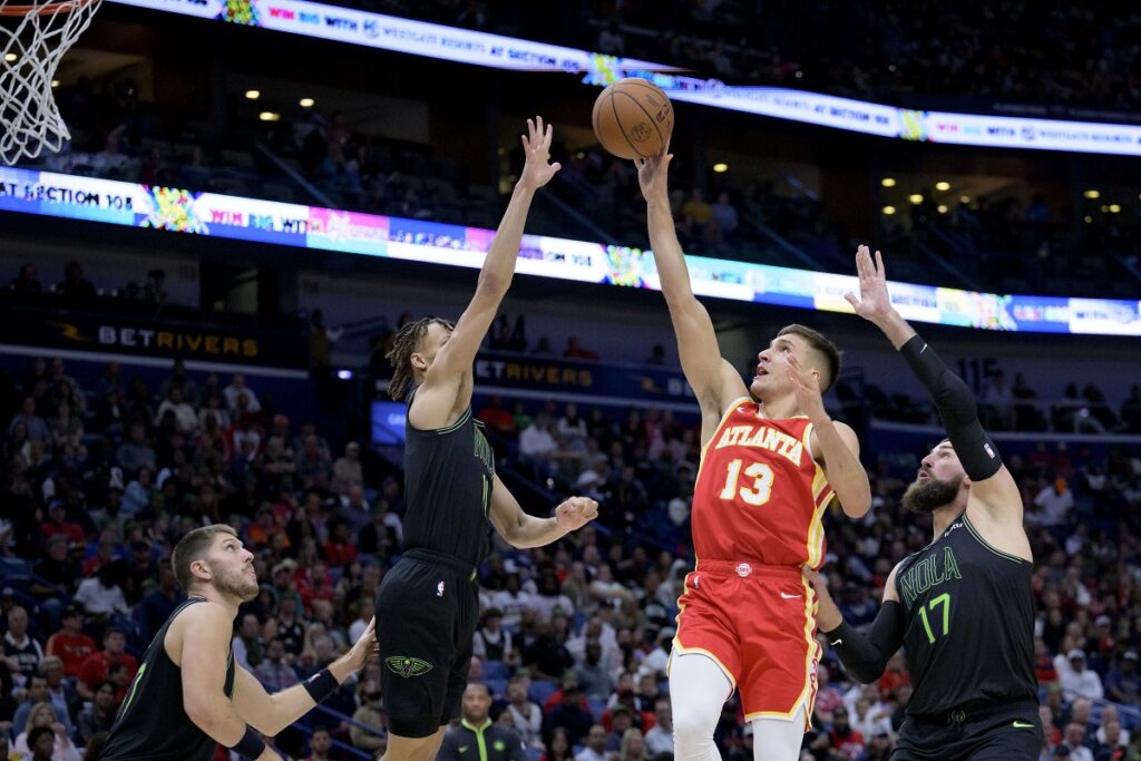 Atlanta Hawks guard Bogdan Bogdanovic (13) shoots against New Orleans Pelicans guard Dyson Daniels, center left, during the second half of an NBA basketball game against the New Orleans Pelicans in New Orleans, Saturday, Nov. 4, 2023. (AP Photo/Matthew Hinton)