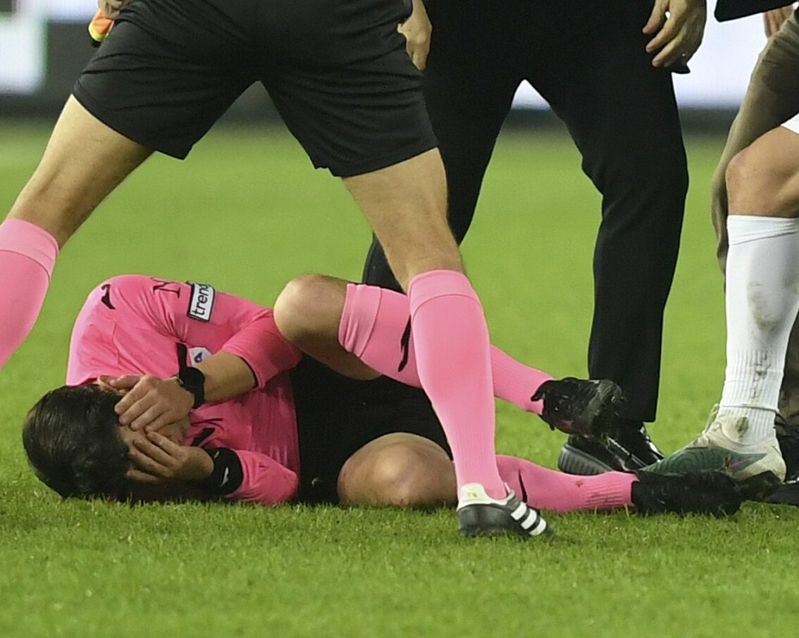 Referee Halil Umut Meler holds his face as he lies on the ground after being punched by MKE Ankaragucu president Faruk Koca, center right, at the end of the Turkish Super Lig soccer match between MKE Ankaragucu and Caykur Rizespor in Ankara, Monday, Dec. 11, 2023. The Turkish Football Federation has suspended all league games in the country after a club president punched the referee in the face at the end of a top-flight match. Koca was arrested Tuesday, Dec. 12, 2023, along with two other people on charges of injuring a public official following questioning by prosecutors. (Abdurrahman Antakyali/Depo Photos via AP)