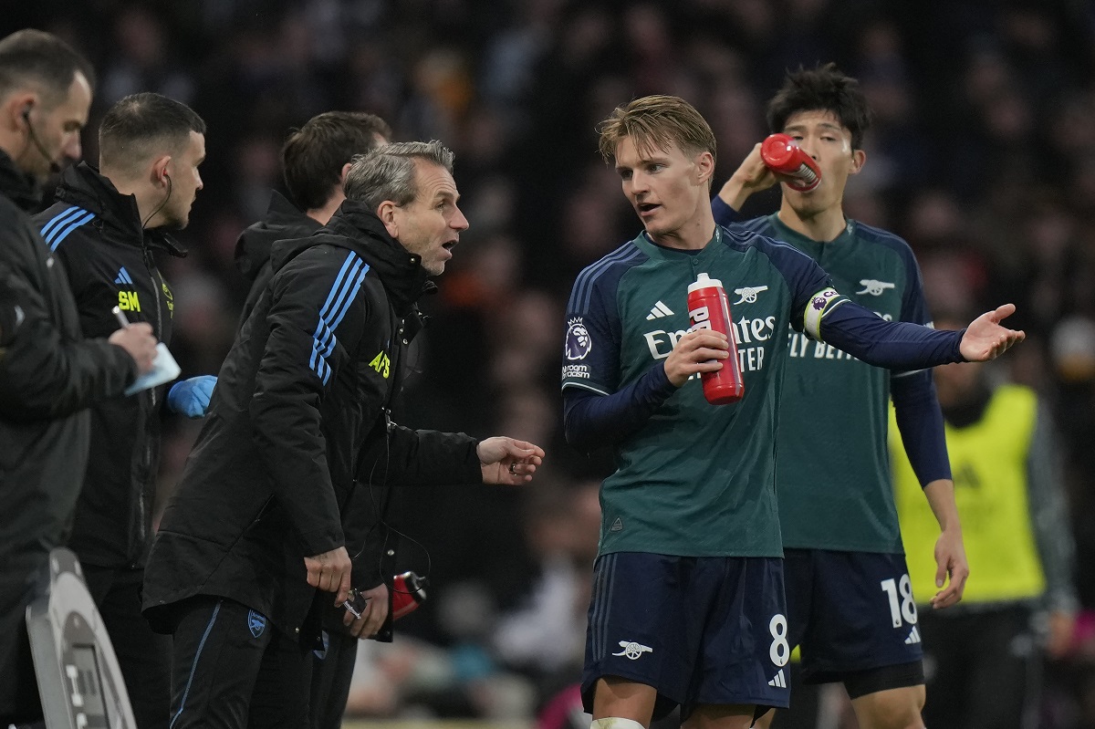 Arsenal's Martin Odegaard, second right, speaks to members of team support staff during the English Premier League soccer match between Arsenal and Fulham at Craven Cottage stadium in London, Sunday, Dec. 31, 2023. (AP Photo/Alastair Grant)