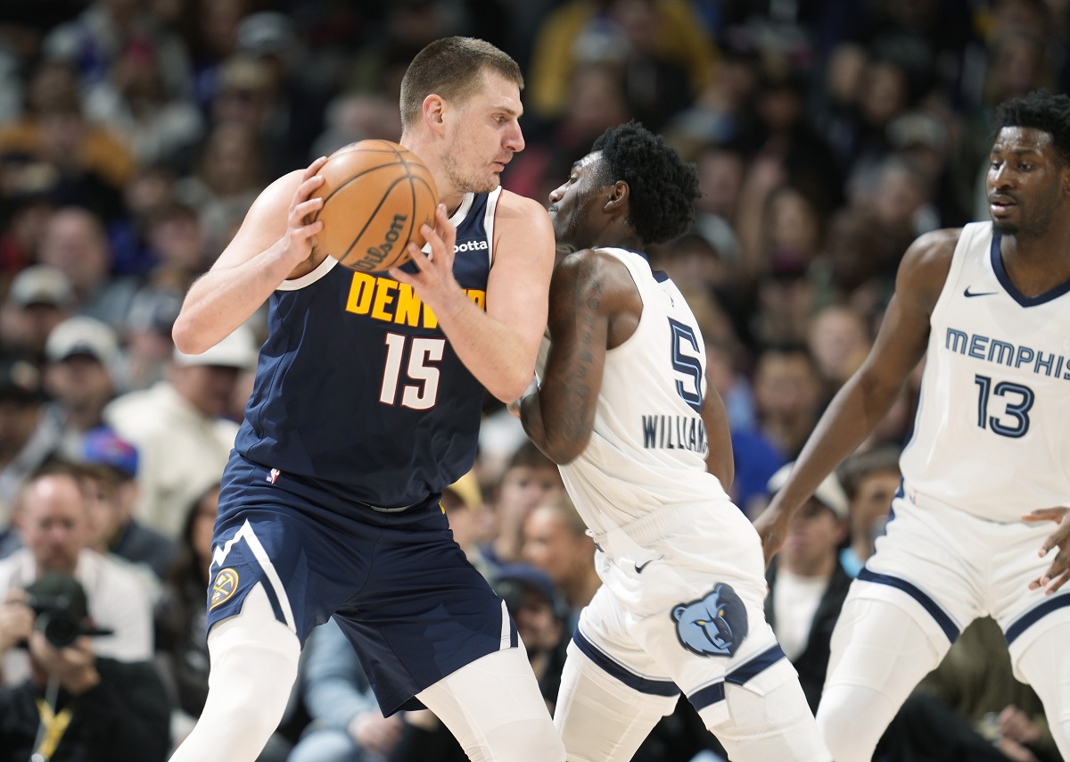 Denver Nuggets center Nikola Jokic, left, looks to drive to the basket as Memphis Grizzlies guard Vince Williams Jr., center, and forward Jaren Jackson Jr., right, defend in the second half of an NBA basketball game Thursday, Dec. 28, 2023, in Denver. (AP Photo/David Zalubowski)