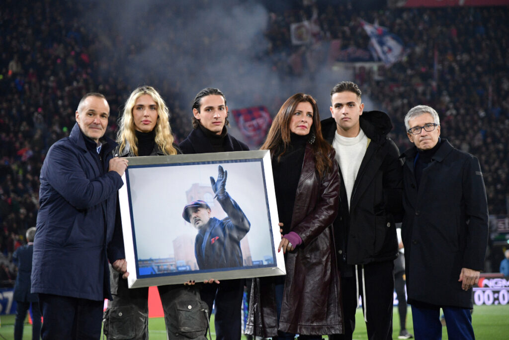 Family members hold a photo in remembrance of the one year anniversary of the death of Sinisa Mihajlovic, ahead of the Italian Serie A soccer match between Bolgna and Roma, at Renato Dall'Ara Stadium, in Bologna, Italy, Sunday, Dec. 17, 2023. (Massimo Paolone /LaPresse via AP)