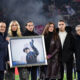 Family members hold a photo in remembrance of the one year anniversary of the death of Sinisa Mihajlovic, ahead of the Italian Serie A soccer match between Bolgna and Roma, at Renato Dall'Ara Stadium, in Bologna, Italy, Sunday, Dec. 17, 2023. (Massimo Paolone /LaPresse via AP)