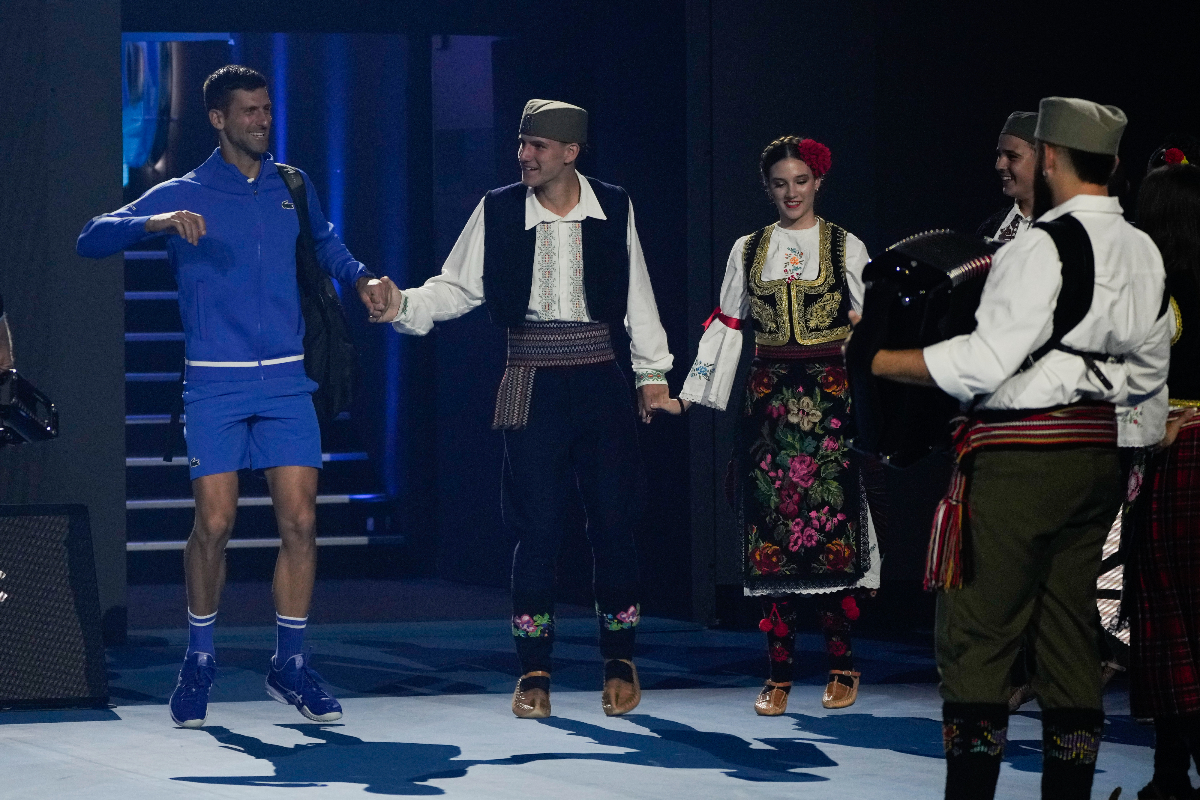 Serbia's Novak Djokovic reacts as he is greeted by dancers as walks onto Rod Laver Arena for an exhibition match against Stefanos Tsitsipas of Greece ahead of the Australian Open tennis championships at Melbourne Park, Melbourne, Australia, Thursday, Jan. 11, 2024. (AP Photo/Andy Wong)