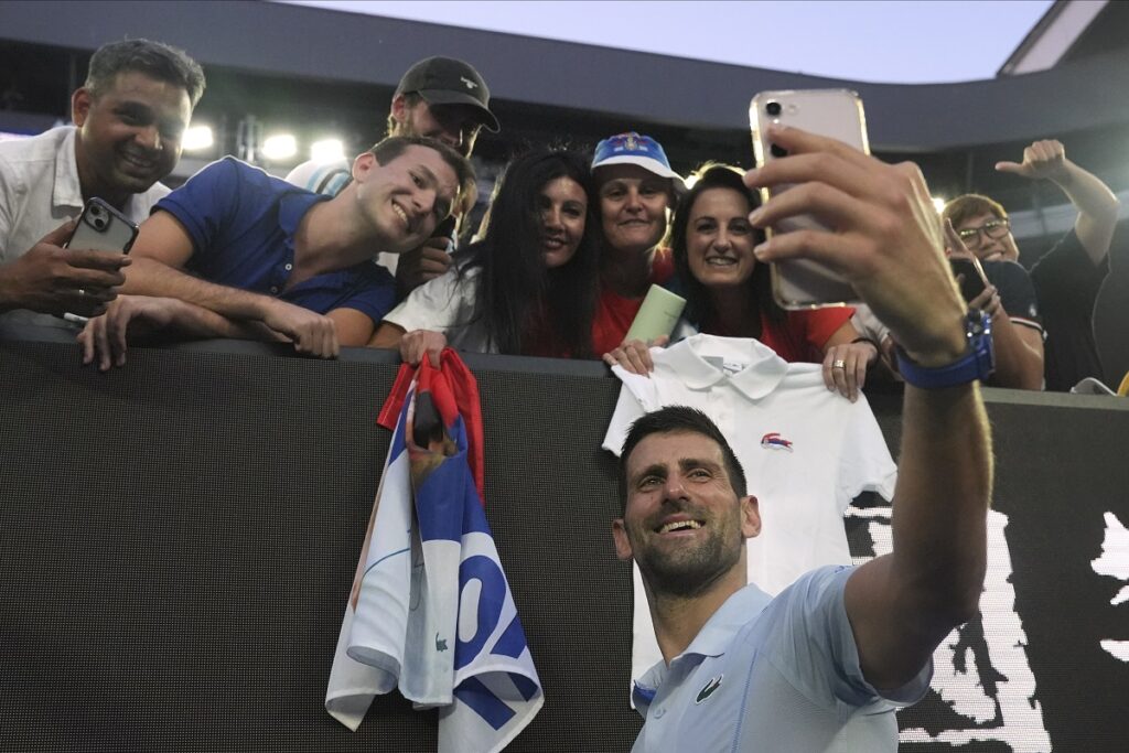 Novak Djokovic of Serbia takes a selfie with fans following his quarterfinal win over Taylor Fritz of the U.S. at the Australian Open tennis championships at Melbourne Park, Melbourne, Australia, Tuesday, Jan. 23, 2024. (AP Photo/Andy Wong)