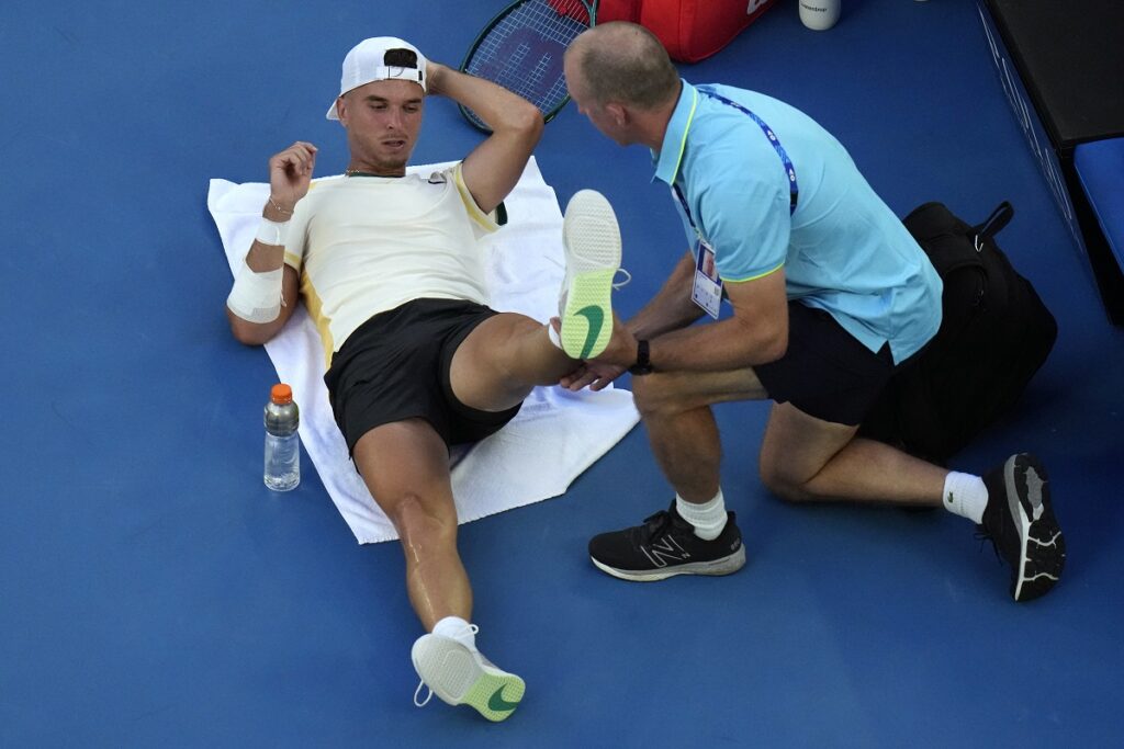 Croatia's Dino Prizmic receives treatment from a trainer during his first round match against Serbia's Novak Djokovic at the Australian Open tennis championships at Melbourne Park, Melbourne, Australia, Sunday, Jan. 14, 2024. (AP Photo/Andy Wong)