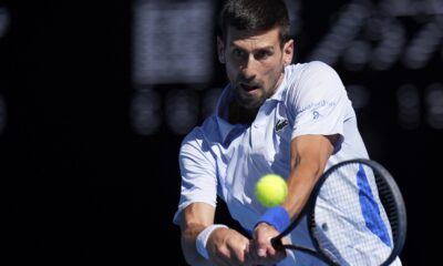 Novak Đoković of Serbia plays a backhand return to Taylor Fritz of the U.S. during their quarterfinal match at the Australian Open tennis championships at Melbourne Park, Melbourne, Australia, Tuesday, Jan. 23, 2024. (AP Photo/Andy Wong)