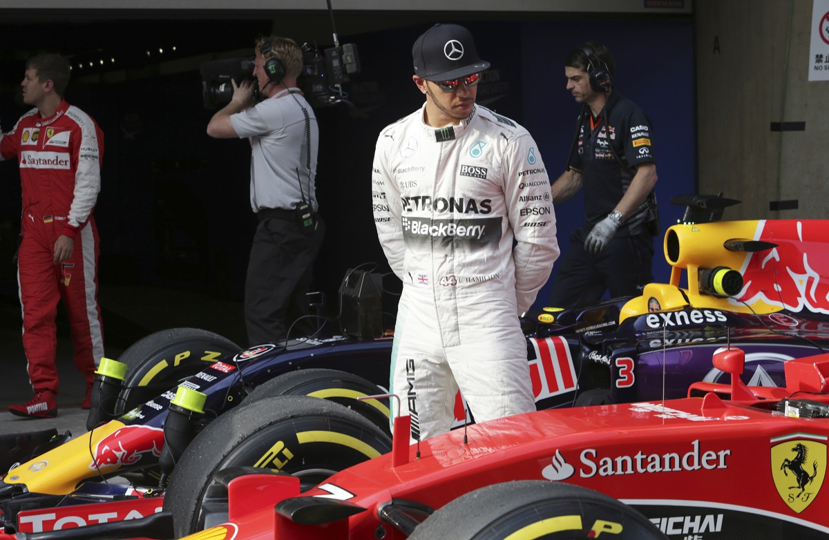 FILE - Mercedes driver Lewis Hamilton of Britain looks at Finnish driver Kimi Raikkonen's Ferrari after getting pole in the qualifying session for the Chinese Formula One Grand Prix at Shanghai International Circuit in Shanghai, China, Saturday, April 11, 2015. Seven-time Formula One champion Lewis Hamilton has been linked with a shock move from Mercedes to Ferrari next year. (AP Photo/Toru Takahashi, File)