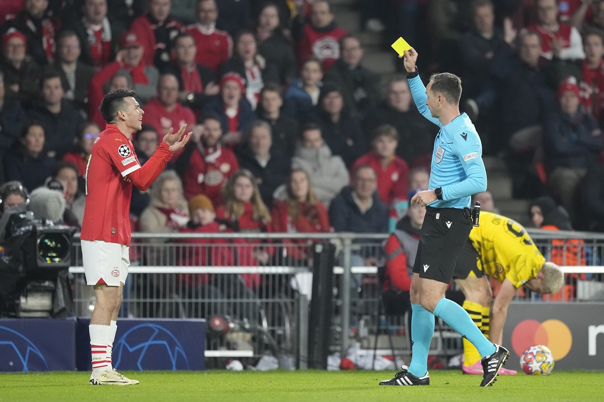 PSV's Hirving Lozano, left, is shown a yellow card by Serbian referee Srdjan Jovanovic during the Champions League round of 16 first leg soccer match between PSV Eindhoven and Borussia Dortmund at Philips stadium in Eindhoven, Netherlands, Tuesday, Feb. 20, 2024. (AP Photo/Peter Dejong)