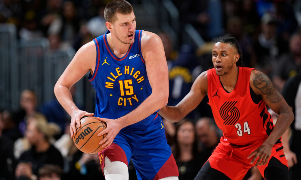 Denver Nuggets center Nikola Jokic, left, looks to pass the ball as Portland Trail Blazers forward Jabari Walker defends in the first half of an NBA basketball game Friday, Feb. 2, 2024, in Denver. (AP Photo/David Zalubowski)