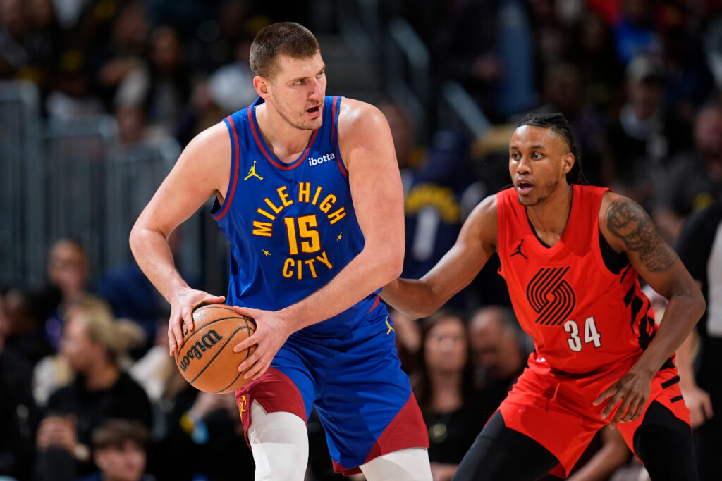 Denver Nuggets center Nikola Jokic, left, looks to pass the ball as Portland Trail Blazers forward Jabari Walker defends in the first half of an NBA basketball game Friday, Feb. 2, 2024, in Denver. (AP Photo/David Zalubowski)