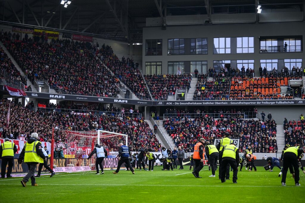 Members of the security staff pick up candy egs during a fan protest during the Bundesliga soccer match between SC Freiburg and Eintracht Frankfurt in Freiburgm Germany, Sunday, Feb. 18, 2024. (Tom Weller/dpa via AP)