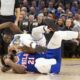 Golden State Warriors forward Draymond Green (23) falls over Philadelphia 76ers center Joel Embiid (21) on an offensive foul by Embiid during the first half of an NBA basketball game, Tuesday, Jan. 30, 2024, in San Francisco. (AP Photo/D. Ross Cameron)