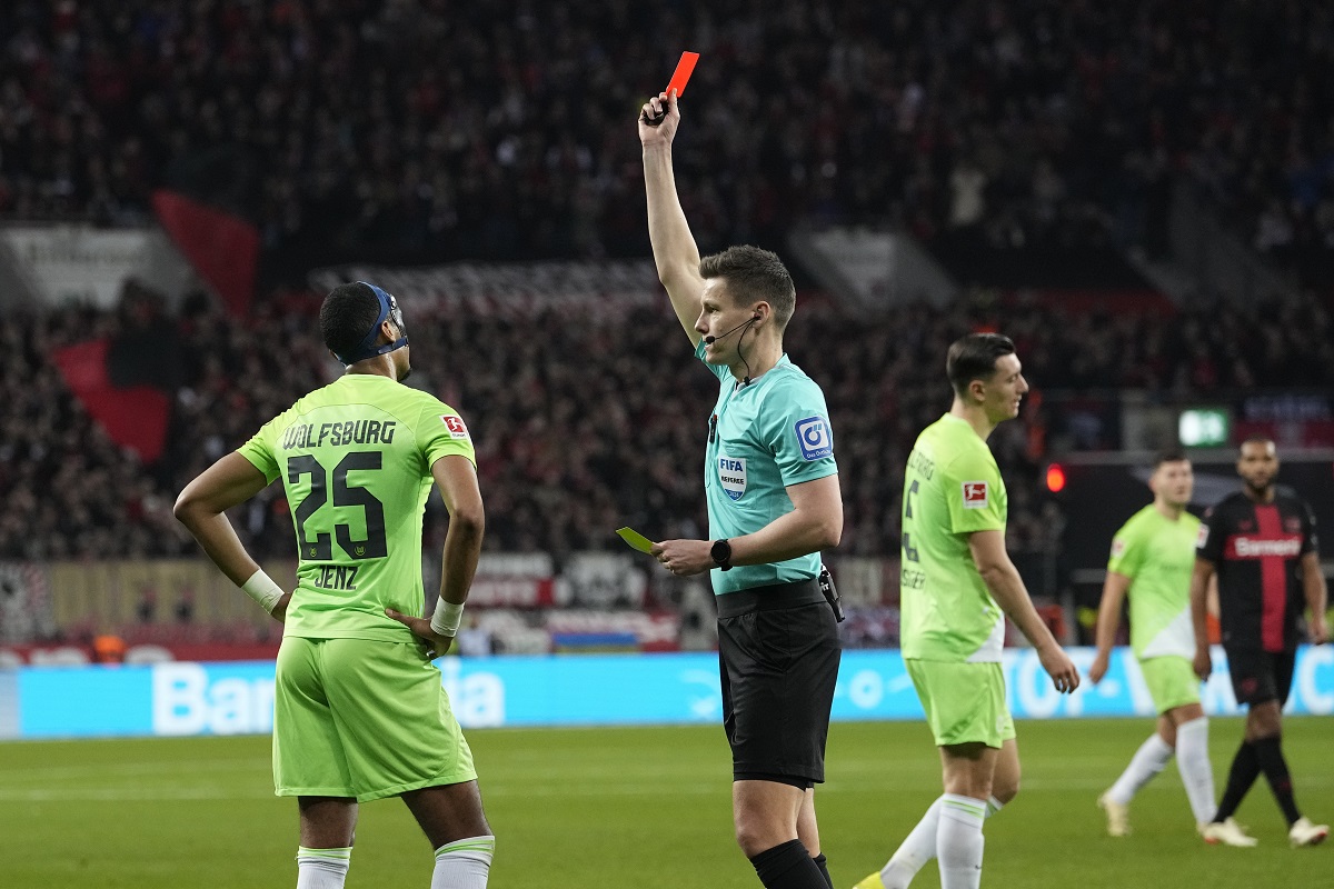 Referee Daniel Siebert shows the red card to Wolfsburg's Moritz Jenz, left, during the German Bundesliga soccer match between Bayer Leverkusen and VfL Wolfsburg at the BayArena in Leverkusen, Germany, Sunday, March 10, 2024. (AP Photo/Martin Meissner)