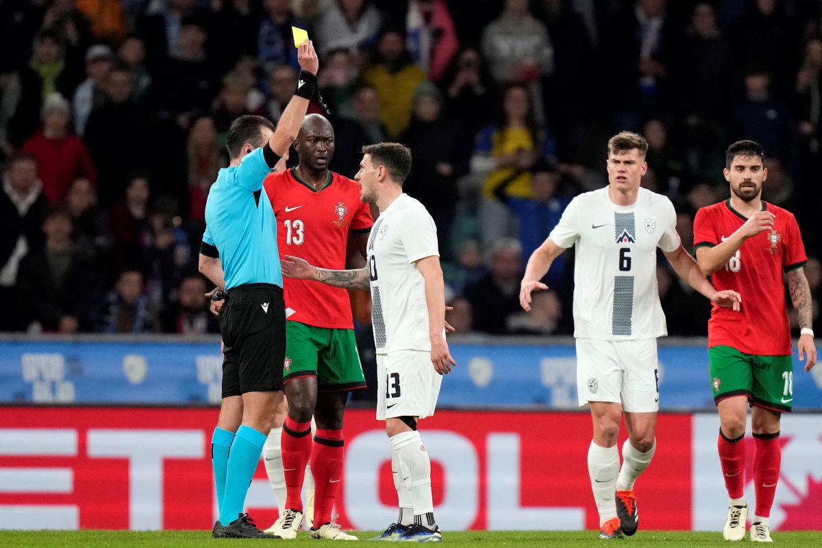 Referee Irfan Peljto shows a yellow card to Slovenia's Erik Janza, center, during the international friendly soccer match between Slovenia and Portugal at the Stozice stadium in Ljubljana, Slovenia, Tuesday, March 26, 2024. (AP Photo/Darko Bandic)
