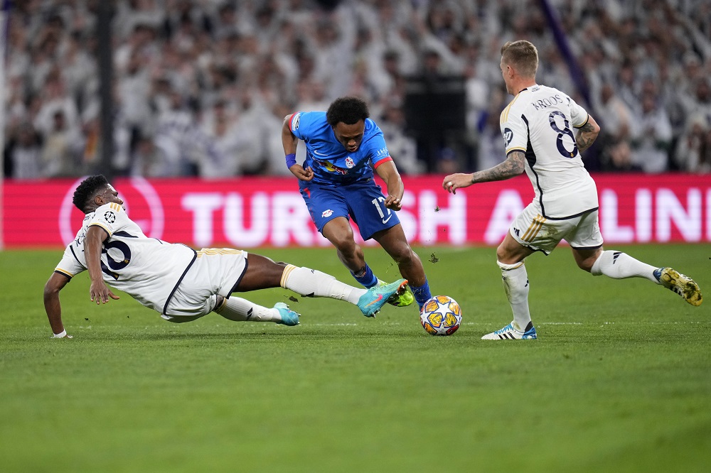 Leipzig's Lois Openda, centre, tries to dribble past Real Madrid's Aurelien Tchouameni, left, and Real Madrid's Toni Kroos during the Champions League round of 16 second leg soccer match between Real Madrid and RB Leipzig at the Santiago Bernabeu stadium in Madrid, Spain, Wednesday, March 6, 2024. (AP Photo/Manu Fernandez)