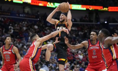 Phoenix Suns guard Devin Booker (1) goes to the basket between New Orleans Pelicans guard CJ McCollum (3) and forward Herbert Jones (5) in the second half of an NBA basketball game in New Orleans, Monday, April 1, 2024. The Suns won 124-111. (AP Photo/Gerald Herbert)