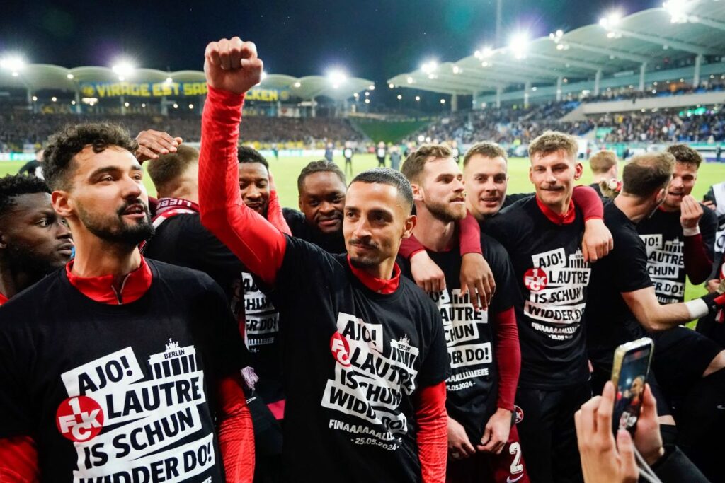 Kaiserslautern's players wear T-shirts with the slogan "Ajo! Lautre is schun widder do!" and celebrate after the final whistle at the German Soccer Cup semifinal soccer match between 1. FC Saarbrucken and 1. FC Kaiserslautern at Ludwigspark Stadium in Saarbrucken, Germany, Tuesday, April 2, 2024. (Uwe Anspach/dpa via AP)