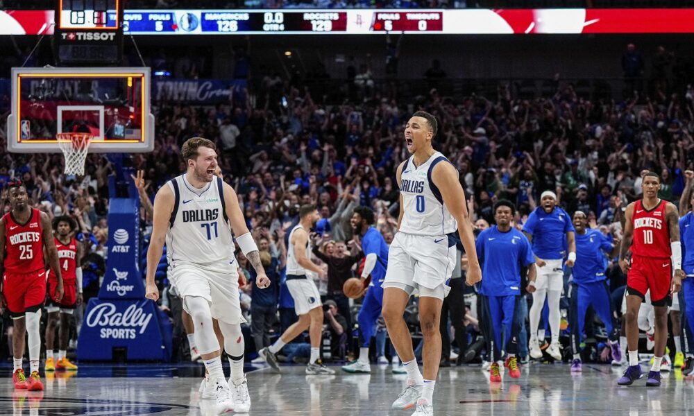 This handout photo provided by the Dallas Mavericks shows Dallas Mavericks guard Dante Exum (0) celebrating his last second three pointer with teammate Luka Doncic (77) as Houston Rockets defenders Reggie Bullock Jr. (25), Jabari Smith Jr. (10) and Jalen Green (4) look on at the end of the fourth quarter of an NBA basketball game Sunday, April 7, 2024 in Dallas. (Dallas Mavericks via AP)