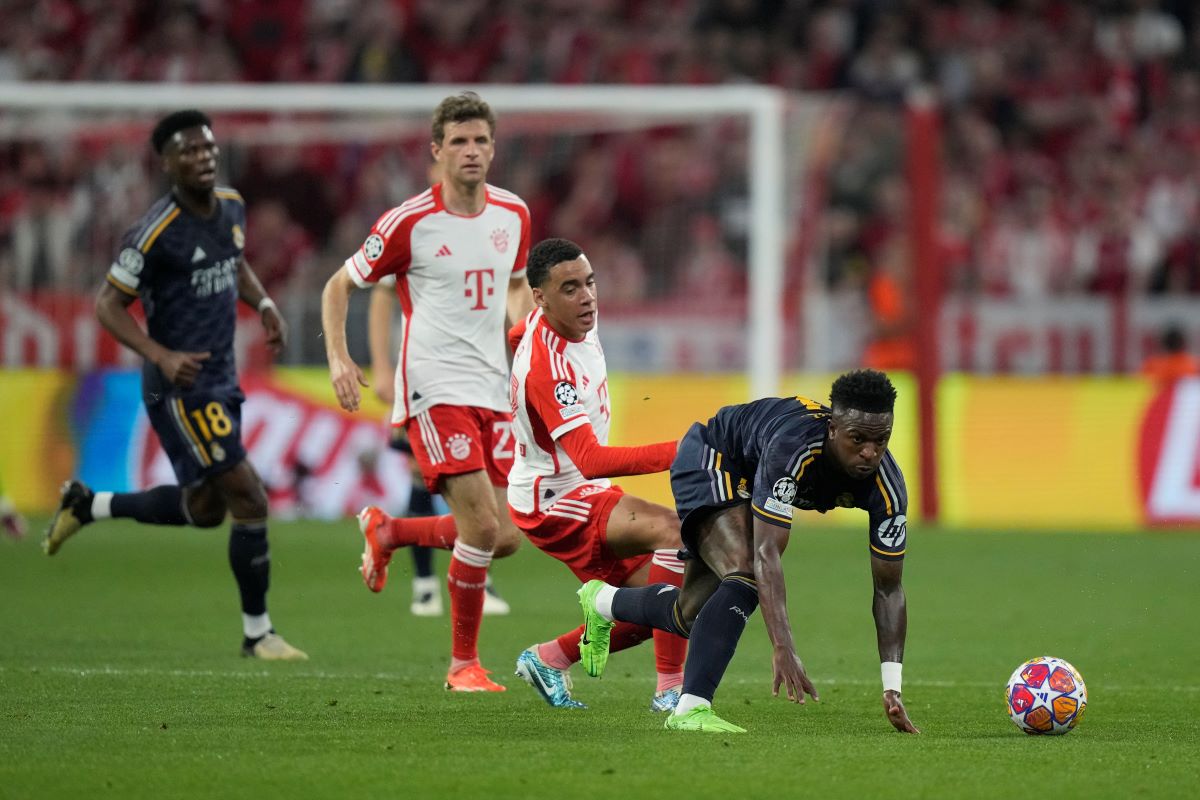 Real Madrid's Vinicius Junior, right, is challenged by Bayern's Jamal Musiala during the Champions League semifinal first leg soccer match between Bayern Munich and Real Madrid at the Allianz Arena in Munich, Germany, Tuesday, April 30, 2024. (AP Photo/Matthias Schrader)