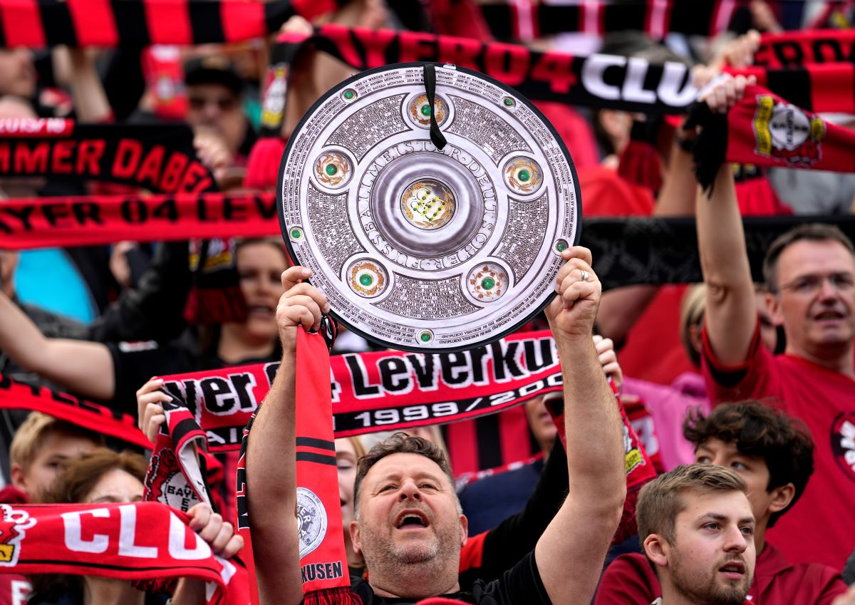 A supporter holds up a makeshift trophy ahead of the German Bundesliga soccer match between Bayer Leverkusen and Werder Bremen in Leverkusen, Germany, Sunday, April 14, 2024. Leverkusen could win the Bundesliga title if they win today's match against Werder Bremen.(AP Photo/Martin Meissner)