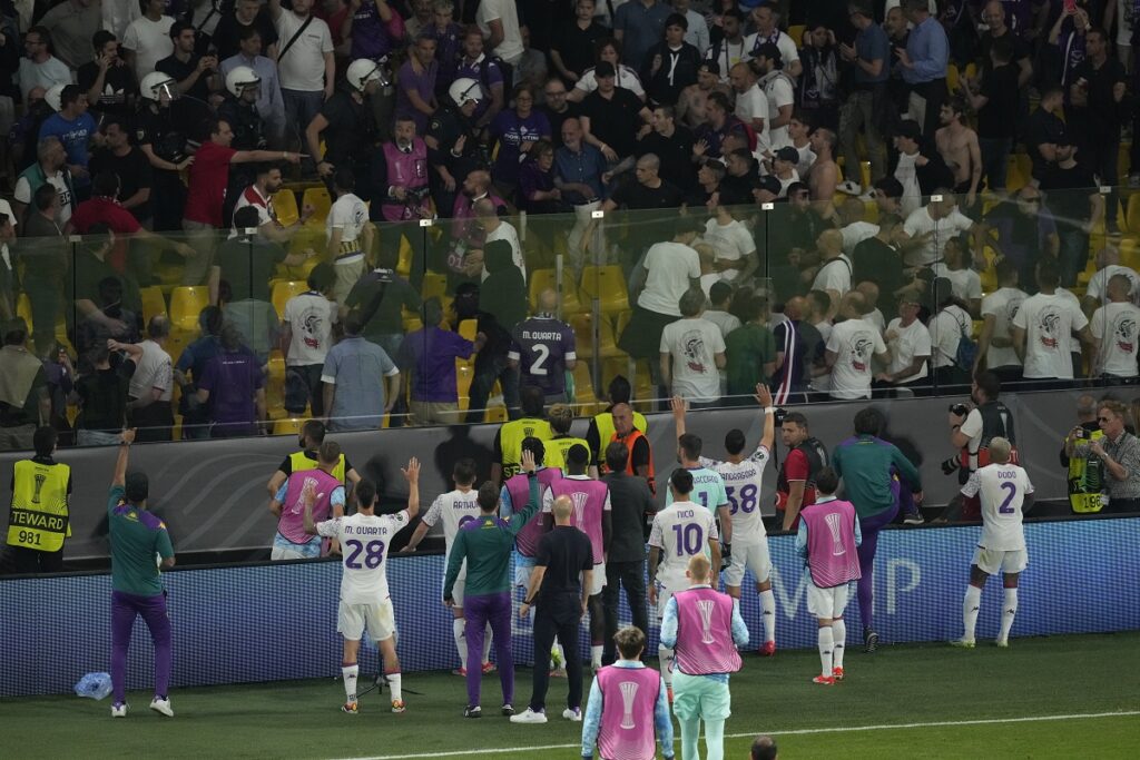 Fiorentina players try to deescalated during their supporters clashes with police at the half time during the Conference League final soccer match between Olympiacos FC and ACF Fiorentina at OPAP Arena in Athens, Greece, Wednesday, May 29, 2024. (AP Photo/Petros Karadjias)
