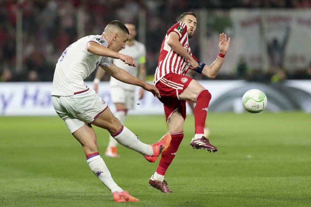 Olympiacos' Kostas Fortounis, right, tries to block a shot from Fiorentina's Nikola Milenkovic during the Conference League final soccer match between Olympiacos FC and ACF Fiorentina at OPAP Arena in Athens, Greece, Wednesday, May 29, 2024. (AP Photo/Petros Giannakouris)