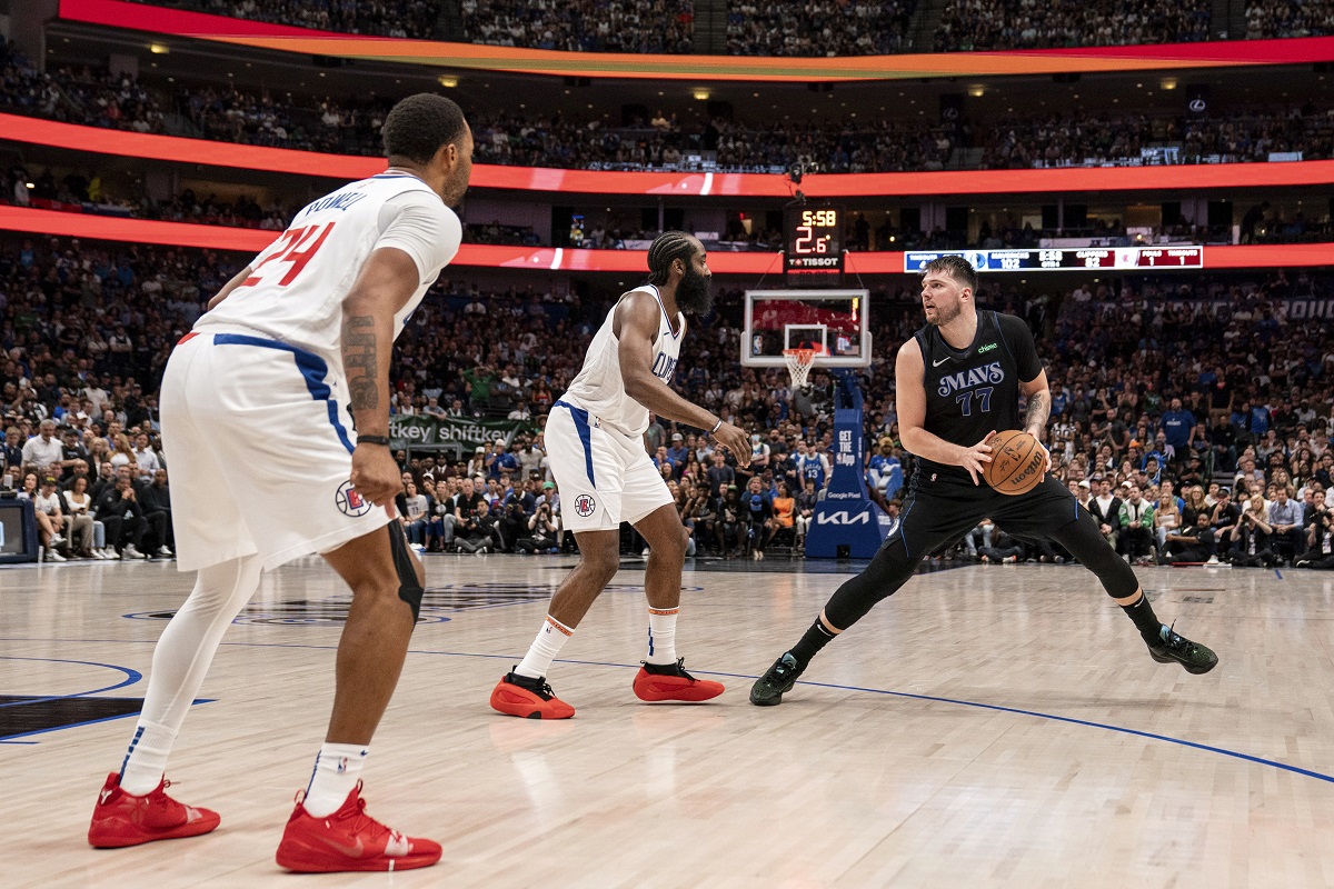 Dallas Mavericks guard Luka Doncic (77) steps back to take a shot in front of Los Angeles Clippers guard James Harden, center, as guard Norman Powell (24) looks on during the second half of an NBA basketball first-round playoff series Friday, May 3, 2024, in Dallas. (AP Photo/Jeffrey McWhorter)