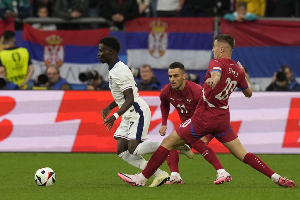 England's Bukayo Saka, left, controls the ball away from Serbia's Filip Kostic, and teammate Sergej Milinkovic-Savic during a Group C match between Serbia and England at the Euro 2024 soccer tournament in Gelsenkirchen, Germany, Sunday, June 16, 2024. (AP Photo/Frank Augstein)