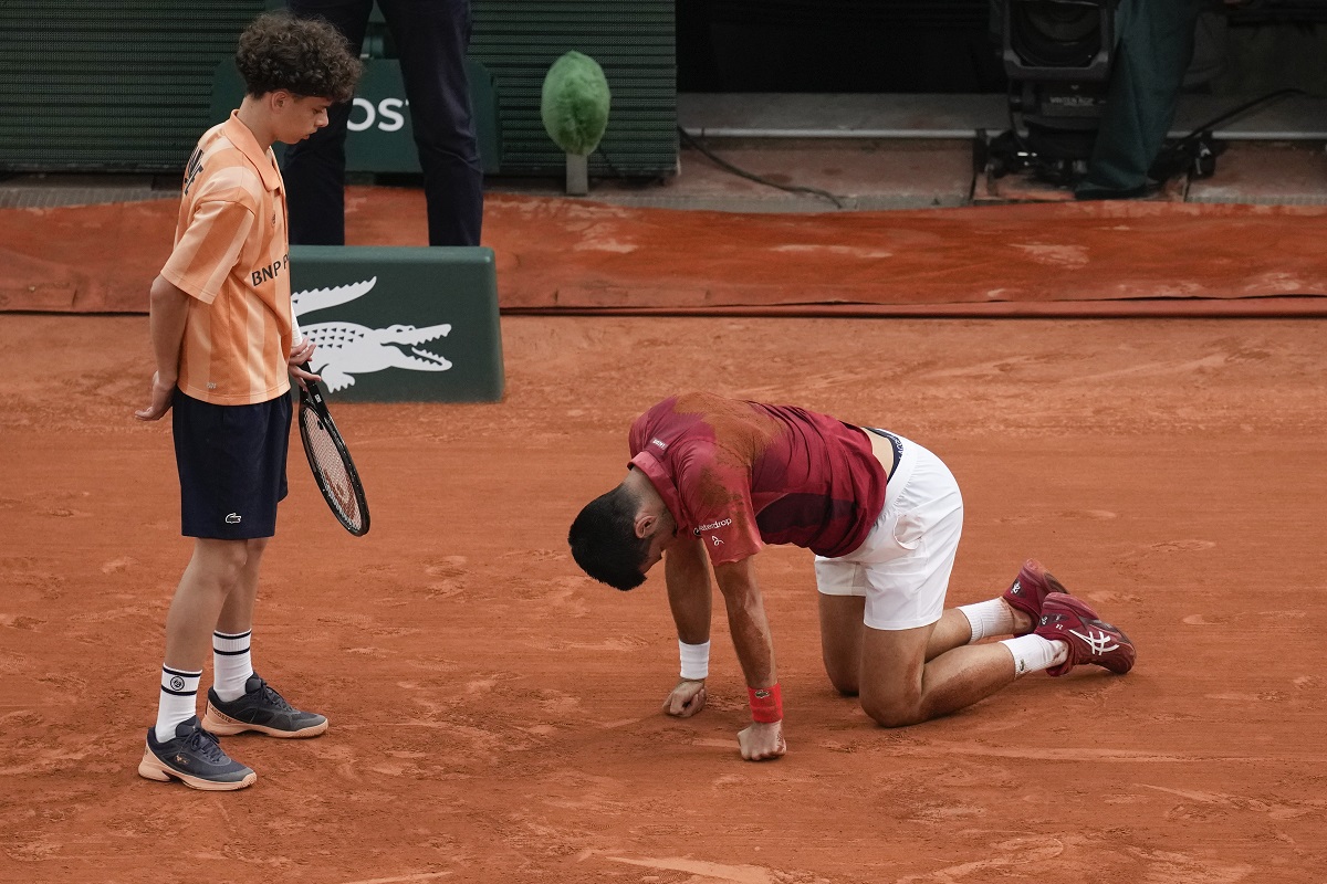 A ball kid came to the aid of Serbia's Novak Djokovic after he slipped and fell during his fourth round match of the French Open tennis tournament against Argentina's Francisco Cerundolo at the Roland Garros stadium in Paris, Monday, June 3, 2024. (AP Photo/Christophe Ena)