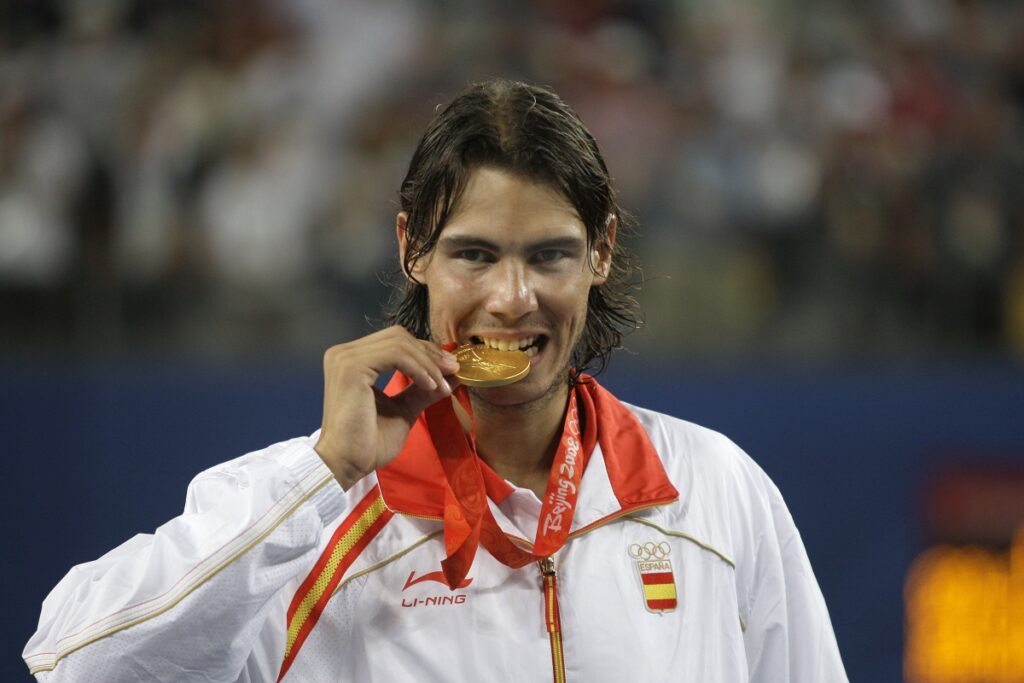 FILE - Rafael Nadal of Spain bites his gold medal for the photographers after beating Fernando Gonzalez of Chile during their Gold medal singles tennis at the Beijing 2008 Olympics in Beijing, Sunday, Aug. 17, 2008. (AP Photo/Elise Amendola, File)