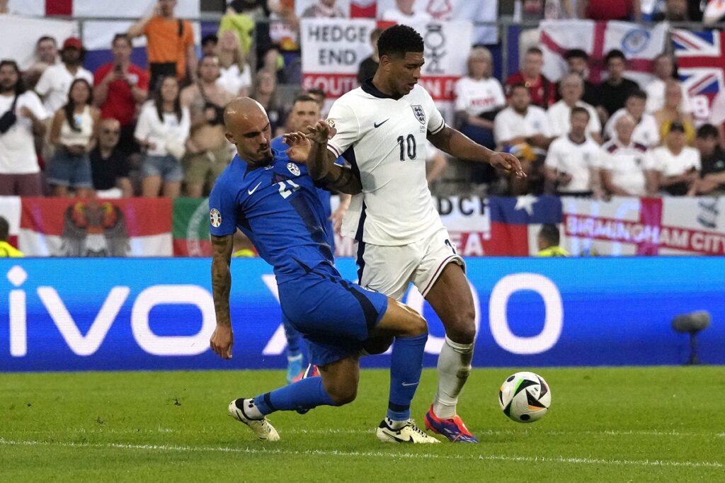 England's Jude Bellingham, right, moves the ball as Slovenia's Vanja Drkusic reaches in during a Group C match between the England and Slovenia at the Euro 2024 soccer tournament in Cologne, Germany, Tuesday, June 25, 2024. (AP Photo/Frank Augstein)