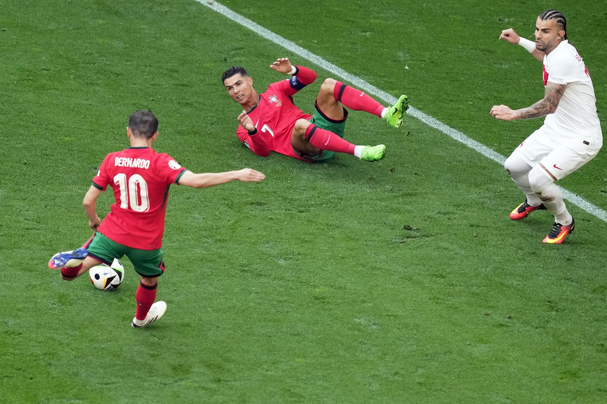 Portugal's Cristiano Ronaldo, on the ground, watches as teammate Bernardo Silva scores the opening goal during a Group F match between Turkey and Portugal at the Euro 2024 soccer tournament in Dortmund, Germany, Saturday, June 22, 2024. (AP Photo/Michael Probst)