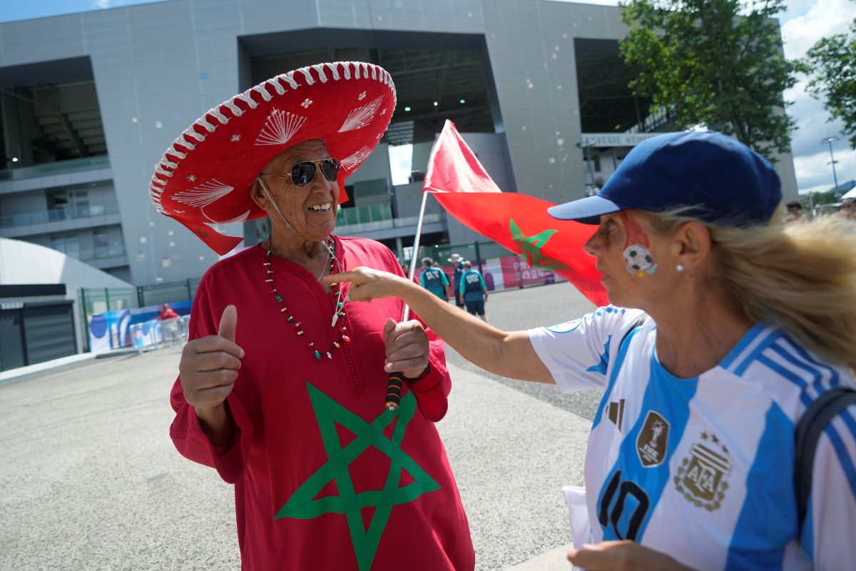 Celia Vicente, 68, of Argentina, right, talks with a supporter of Morocco, before the men's Group B soccer match between Argentina and Morocco at the Geoffroy-Guichard Stadium during the 2024 Summer Olympics, Wednesday, July 24, 2024, in Saint-Etienne, France. (AP Photo/Silvia Izquierdo)