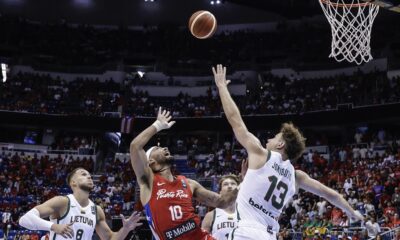 Puerto Rico's Jose Alvarado, center, launches a shot over Lithuania's Rokas Jokubaitis, right, during the final game of the FIBA Olympic qualifying tournament in San Juan, Puerto Rico, Sunday, July 7, 2024. (AP Photo/Alejandro Granadillo)