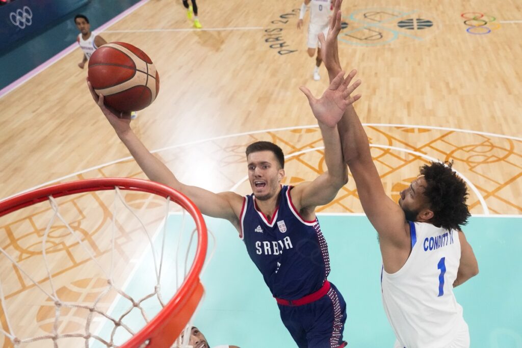 Filip Petrusev, of Serbia, shoots around dGeorge Conditt IV, of Puerto Rico, in a men's basketball game in a men's basketball game at the 2024 Summer Olympics, Wednesday, July 31, 2024, in Villeneuve-d'Ascq, France. (AP Photo/Mark J. Terrill, Pool)