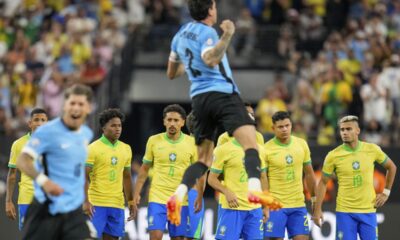 Payers of Brazil stand on the midfield as players of Uruguay celebrate their win in a penalty shootout during a Copa America quarterfinal soccer match in Las Vegas, Saturday, July 6, 2024. (AP Photo/Julio Cortez)