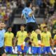 Payers of Brazil stand on the midfield as players of Uruguay celebrate their win in a penalty shootout during a Copa America quarterfinal soccer match in Las Vegas, Saturday, July 6, 2024. (AP Photo/Julio Cortez)