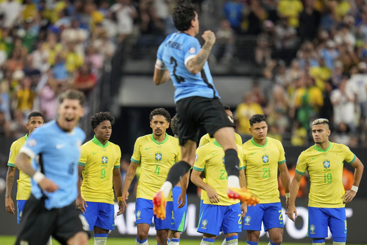 Payers of Brazil stand on the midfield as players of Uruguay celebrate their win in a penalty shootout during a Copa America quarterfinal soccer match in Las Vegas, Saturday, July 6, 2024. (AP Photo/Julio Cortez)