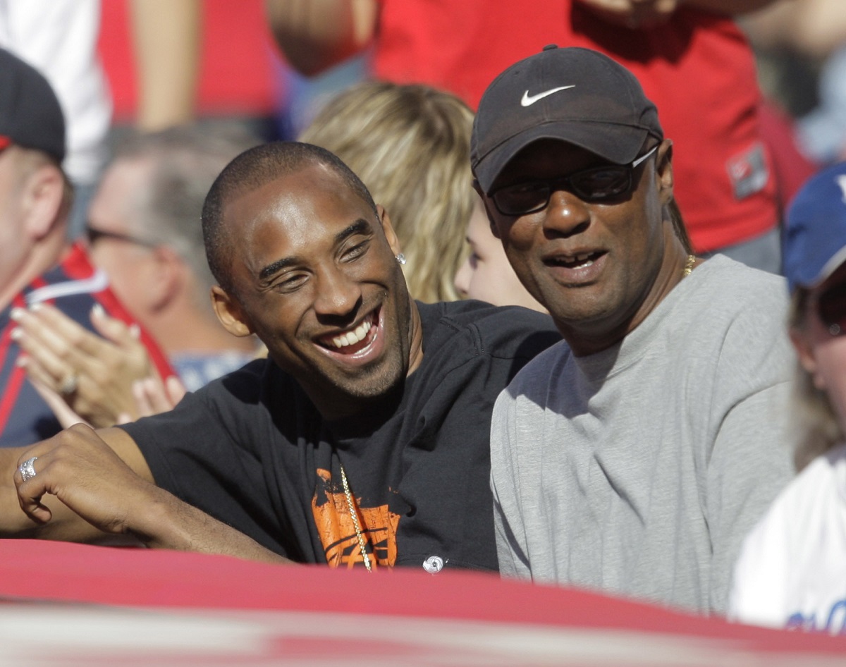 FILE - Los Angeles Lakers' Kobe Bryant, left, talks to his father, Joe, as they watch a baseball game between the Los Angeles Angels and the Los Angeles Dodgers in Anaheim, Calif., Sunday, June 21, 2009. Joe “Jellybean” Bryant has died, his alma mater announced Tuesday, July 16, 2024. Joe Bryant, who spent eight seasons in the NBA with three different franchises, was 69. The Philadelphia Inquirer, citing La Salle coach Fran Dunphy, reported that Joe Bryant recently had a massive stroke. (AP Photo/Jae C. Hong, File)