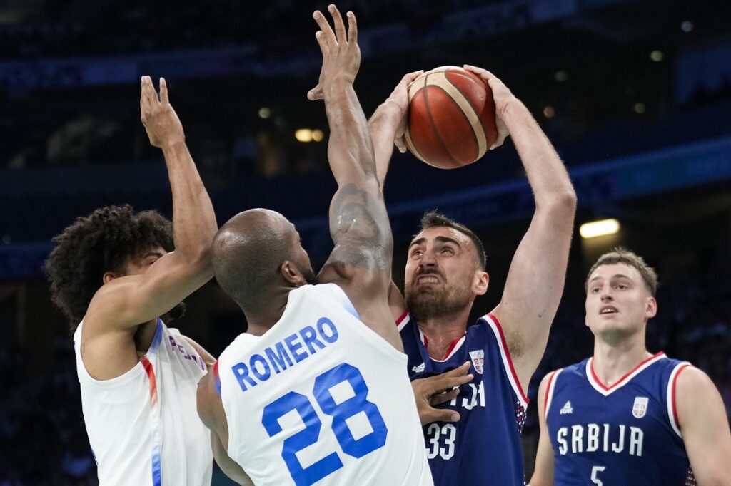 Nikola Milutinov, of Serbia, shoots over Ismael Romero, of Puerto Rico, in a men's basketball game at the 2024 Summer Olympics, Wednesday, July 31, 2024, in Villeneuve-d'Ascq, France. (AP Photo/Mark J. Terrill)