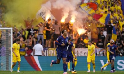 Virgil van Dijk of the Netherlands, center, runs while Romania supporters light flares on the stands during a round of sixteen match between Romania and the Netherlands at the Euro 2024 soccer tournament in Munich, Germany, Tuesday, July 2, 2024. (AP Photo/Manu Fernandez)