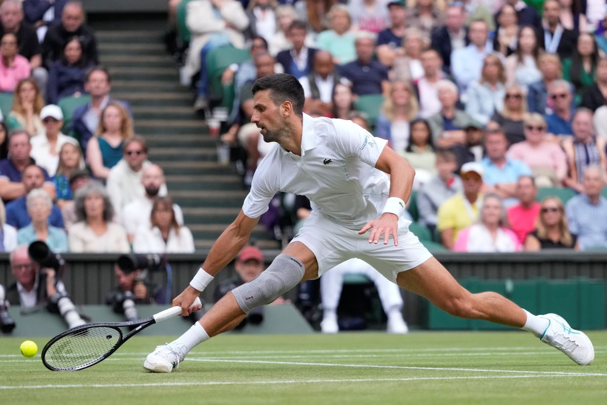 Novak Djokovic of Serbia plays a backhand return to Lorenzo Musetti of Italy during their semifinal match at the Wimbledon tennis championships in London, Friday, July 12, 2024. (AP Photo/Kirsty Wigglesworth)